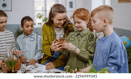 Young teacher learning pupils how to take care about plants. Royalty-Free Stock Photo #2296999345
