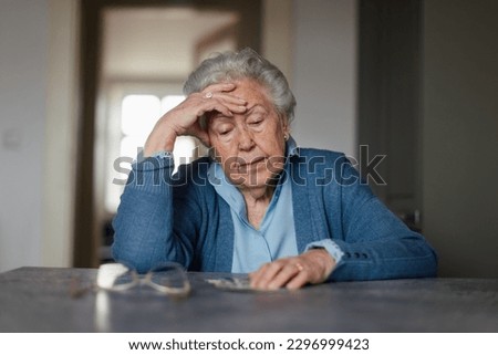 Senior woman counting her money at home. Royalty-Free Stock Photo #2296999423