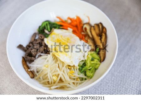 Vibrant and colorful bibimbap bowl filled with fresh and healthy vegetables, symbolizing a nutritious meal and the importance of a balanced diet for overall well-being Royalty-Free Stock Photo #2297002311