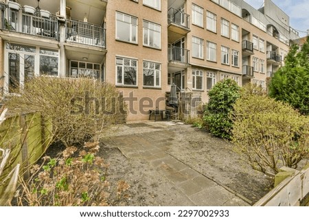 an outside area with some plants and bushes in the fore - eyed photo is taken to the right side of the building