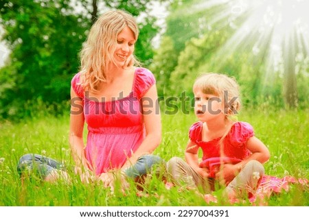 Happy pregnant woman with baby on nature in the park