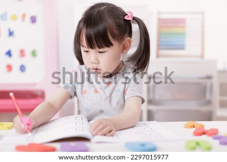 young girl practice writing letters for homeschooling Royalty-Free Stock Photo #2297015977