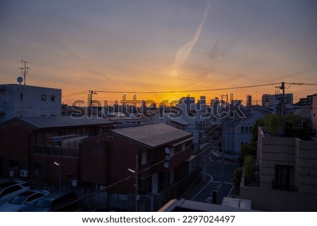 A view of the sunrise in Tokyo. An early morning in a residential area. There are silhouette of tall sky scrappers at far distance.  Royalty-Free Stock Photo #2297024497