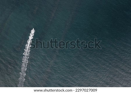 One small boat fast moving at blue sea above top view