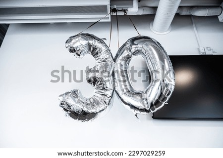 Silver balloons marking 30 year birthday in an office.
