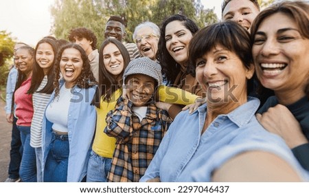 Group of multigenerational people taking selfie with phone camera - Multiracial friends of different ages having fun together - Main focus on asian woman face Royalty-Free Stock Photo #2297046437