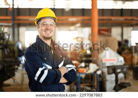 Professional caucasian white ethnicity male technician operating the heavy duty machine in the lathing factory. Technician in safety and helmet suit controlling a machine in factory. Royalty-Free Stock Photo #2297087883