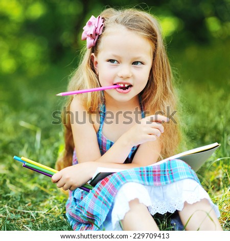 Adorable little girl with pencils and note in a park