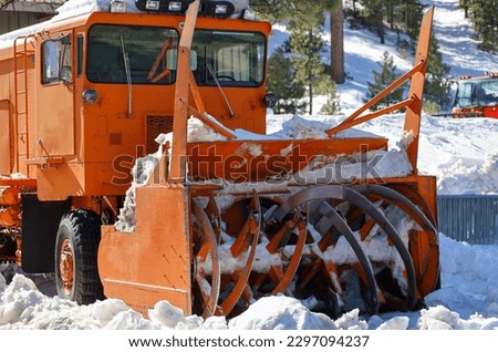 View of a an orange snow plow truck parked.
