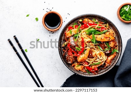 Stir fry noodles with chicken, red paprika, mushrooms, chives and sesame seeds in bowl. Asian cuisine dish. White table background, top view Royalty-Free Stock Photo #2297117153