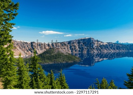 Beautiful Crater Lake National Park with late season snow still lingering into early summer. Bright blue lake with reflections Royalty-Free Stock Photo #2297117291