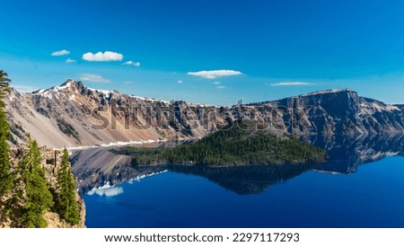 Beautiful Crater Lake National Park with late season snow still lingering into early summer. Bright blue lake with reflections Royalty-Free Stock Photo #2297117293