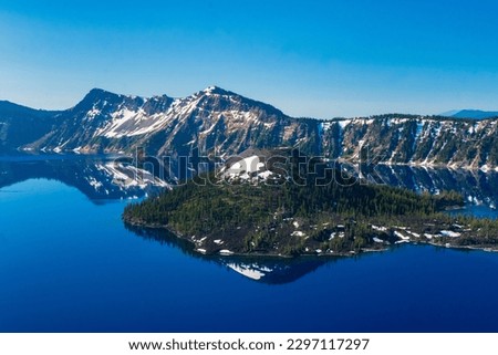 Beautiful Crater Lake National Park with late season snow still lingering into early summer. Bright blue lake with reflections Royalty-Free Stock Photo #2297117297