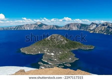 Beautiful Crater Lake National Park with late season snow still lingering into early summer. Bright blue lake with reflections Royalty-Free Stock Photo #2297117315