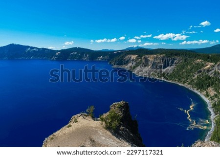 Beautiful Crater Lake National Park with late season snow still lingering into early summer. Bright blue lake with reflections