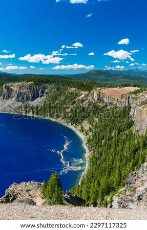 Beautiful Crater Lake National Park with late season snow still lingering into early summer. Bright blue lake with reflections Royalty-Free Stock Photo #2297117325