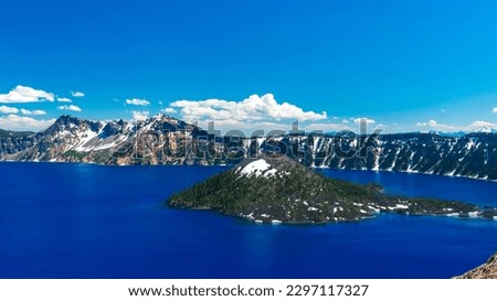 Beautiful Crater Lake National Park with late season snow still lingering into early summer. Bright blue lake with reflections Royalty-Free Stock Photo #2297117327