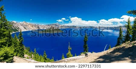 Beautiful Crater Lake National Park with late season snow still lingering into early summer. Bright blue lake with reflections Royalty-Free Stock Photo #2297117331