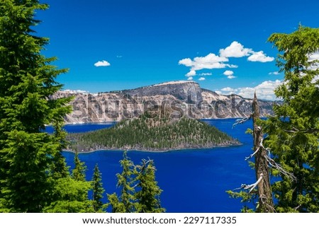 Beautiful Crater Lake National Park with late season snow still lingering into early summer. Bright blue lake with reflections Royalty-Free Stock Photo #2297117335