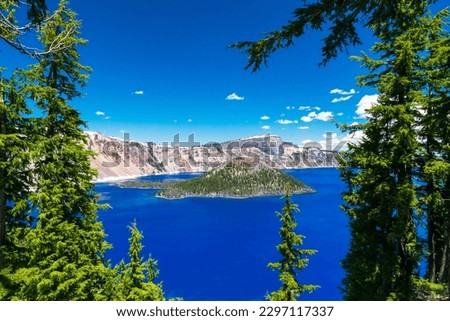 Beautiful Crater Lake National Park with late season snow still lingering into early summer. Bright blue lake with reflections Royalty-Free Stock Photo #2297117337