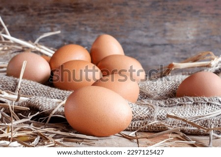 fresh eggs and chicken eggs with dried straw lying on a wooden background table on an organic farm Royalty-Free Stock Photo #2297125427