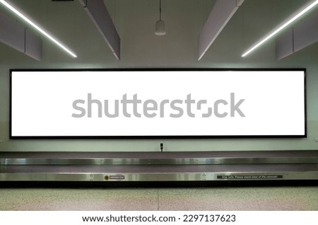Long wide blank white advertisement board mockup template on wall by luggage carousel in a airport.