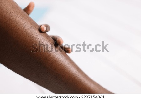Bare legs of African woman closeup, blurred background free copy space. Black person lying with bent legs. Hairy and unshaven legs, new normal, beauty and fashion, body positive. 