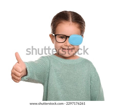 Happy girl with nozzle on glasses for treatment of strabismus showing thumbs up against white background. Space for text