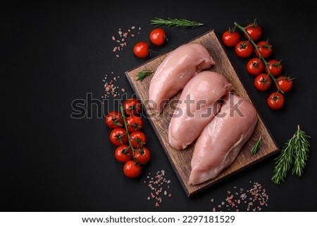 Pieces of raw chicken or turkey fillet with salt, spices and herbs on a dark concrete background Royalty-Free Stock Photo #2297181529