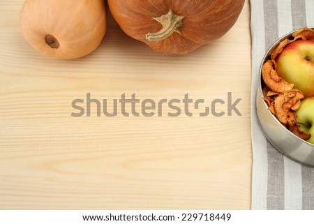 Pumpkin with apples and dried fruits on wooden background with free text space.