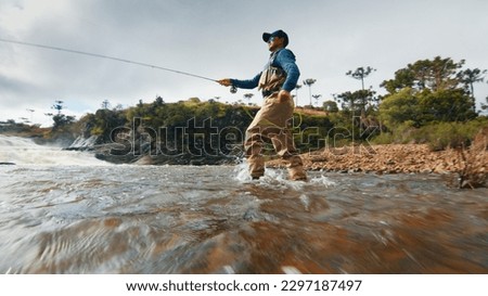Fly fishing. Fisherman in waders fishing on the rapid river Royalty-Free Stock Photo #2297187497