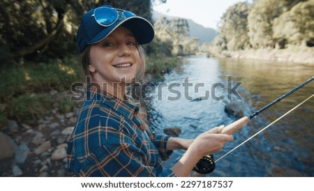 Woman angler on the river. Portrait of the young woman on the river with fishing rod Royalty-Free Stock Photo #2297187537