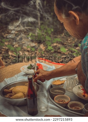 a man sitting at a table with food and a bottle for religious ceremony.