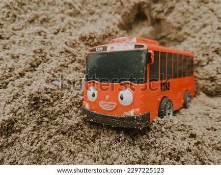 red plastic car toy on the sand