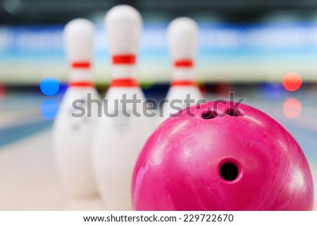 Bowling in details. Close-up of red bowling ball lying against pins staying on bowling alley  