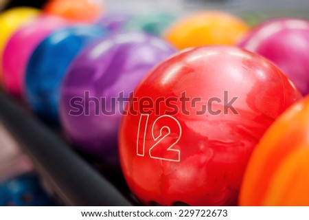 Variety of colors. Close-up of bright red bowling ball lying in the rows of other colorful balls 