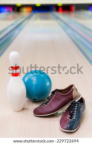 Everything you need for plying bowling. Close-up of bowling shoes, blue ball and pin lying on bowling alley  