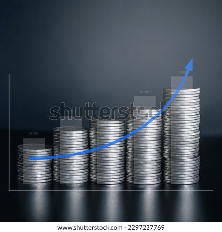 Stack of silver money coin on office desk with growth arrow and graph. Business and financial concept background. 