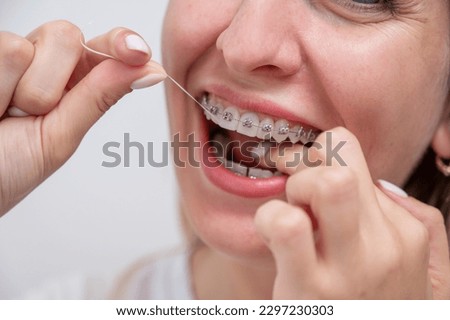 Caucasian woman cleaning her teeth with braces using dental floss. Cropped portrait.  Royalty-Free Stock Photo #2297230303