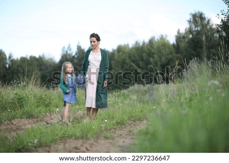 Beautiful young mother with daughter walking on a rural road