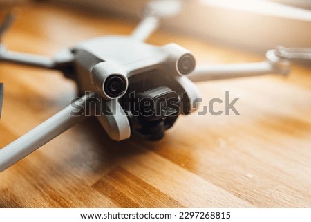 A small size drone placed on a wooden background in front of the window