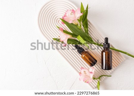 Rejuvenating serum for the face, an organic natural remedy in two glass bottles on a white podium in the form of an arch. Top view. A copy space. Royalty-Free Stock Photo #2297276865