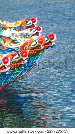 A vertical shot of a colorful wooden dragon boat found anchored at the pier