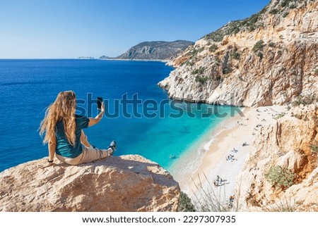 Young woman making selfie photo by smartphone over Kaputas beach, Lycia coast. Summer day walk by Lycian way at family vacation in Mediterranean Sea, Kas, Antalya region, Turkey Royalty-Free Stock Photo #2297307935
