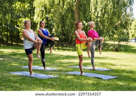 Female yoga class in park during summer. Group of women doing knee to chest pose exercising together Royalty-Free Stock Photo #2297314357