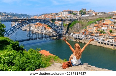 Woman touristwith arms raised enjoying beautiful panoramic view of famous iron bridge and old town- tour tourism in Portugal,  travel in Porto Royalty-Free Stock Photo #2297319437