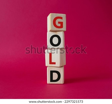 Gold symbol. Concept word Gold on wooden cubes. Beautiful red background. Business and Gold concept. Copy space.