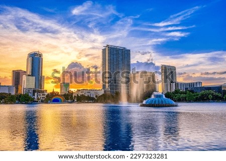 ORLANDO FL, US - May 24, 2022: Sunset and clouds over the Orlando skyline and fountain at Lake Eola Park, Orlando FL Royalty-Free Stock Photo #2297323281