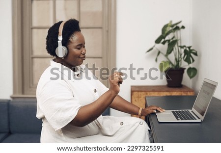 Good music is the ultimate work motivator. a young businesswoman using headphones and a laptop in a modern office.