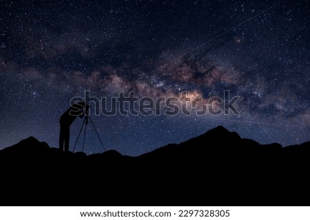 Night sky long exposure landscape. A Camera man standing on a high rock photo the stars rise into the night sky. silhouetted against the milky way galaxy.Photo compsoite.